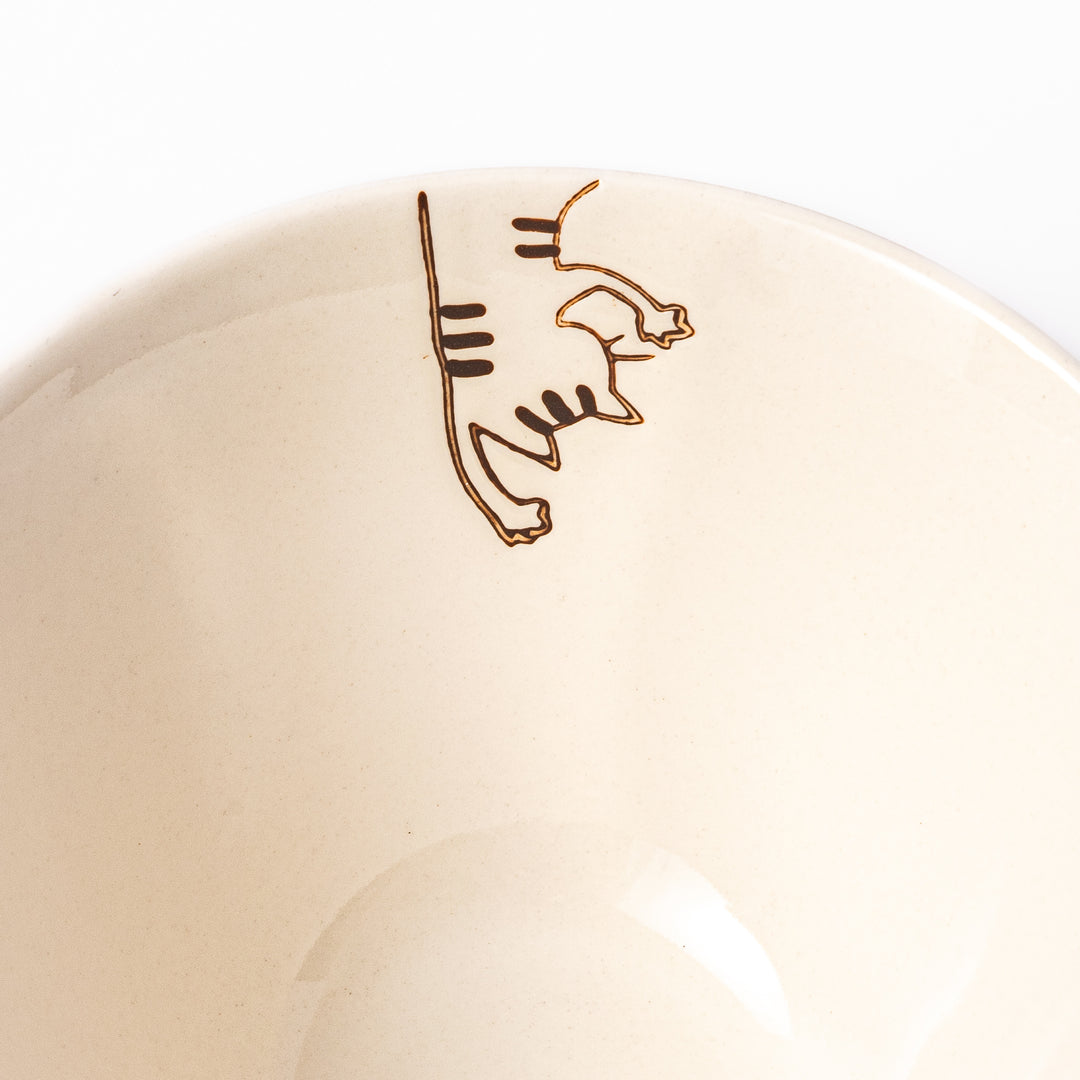 Cream-colored rice bowl with a striped hanging cat, butterfly, and dotted paw prints on the outer and inner surface.