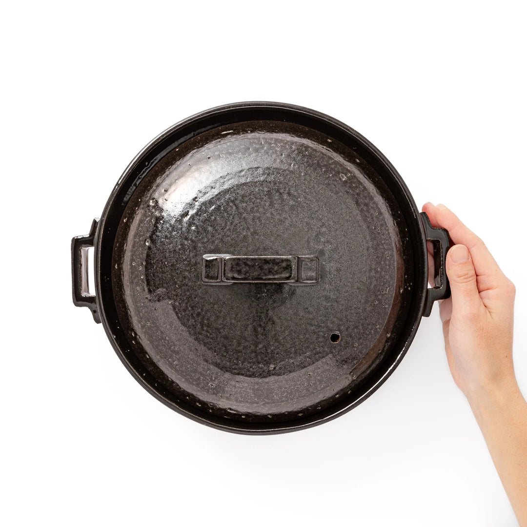 Black Japanese ceramic donabe pot with lid and side handles for simmering and hot pot cooking