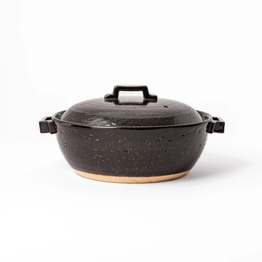 Black Japanese ceramic donabe pot with lid and side handles for simmering and hot pot cooking