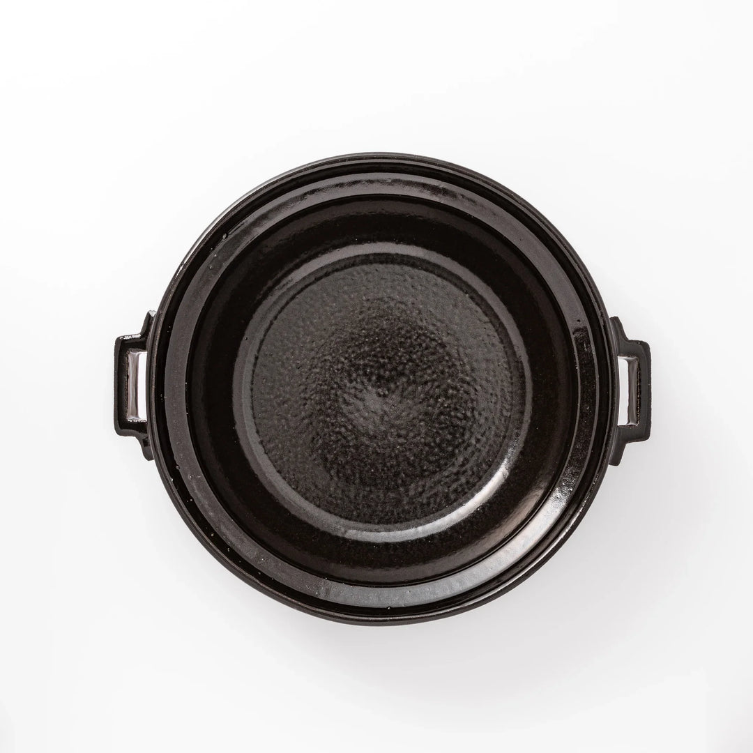 Black Japanese ceramic donabe pot with lid and side handles for simmering and hot pot cooking