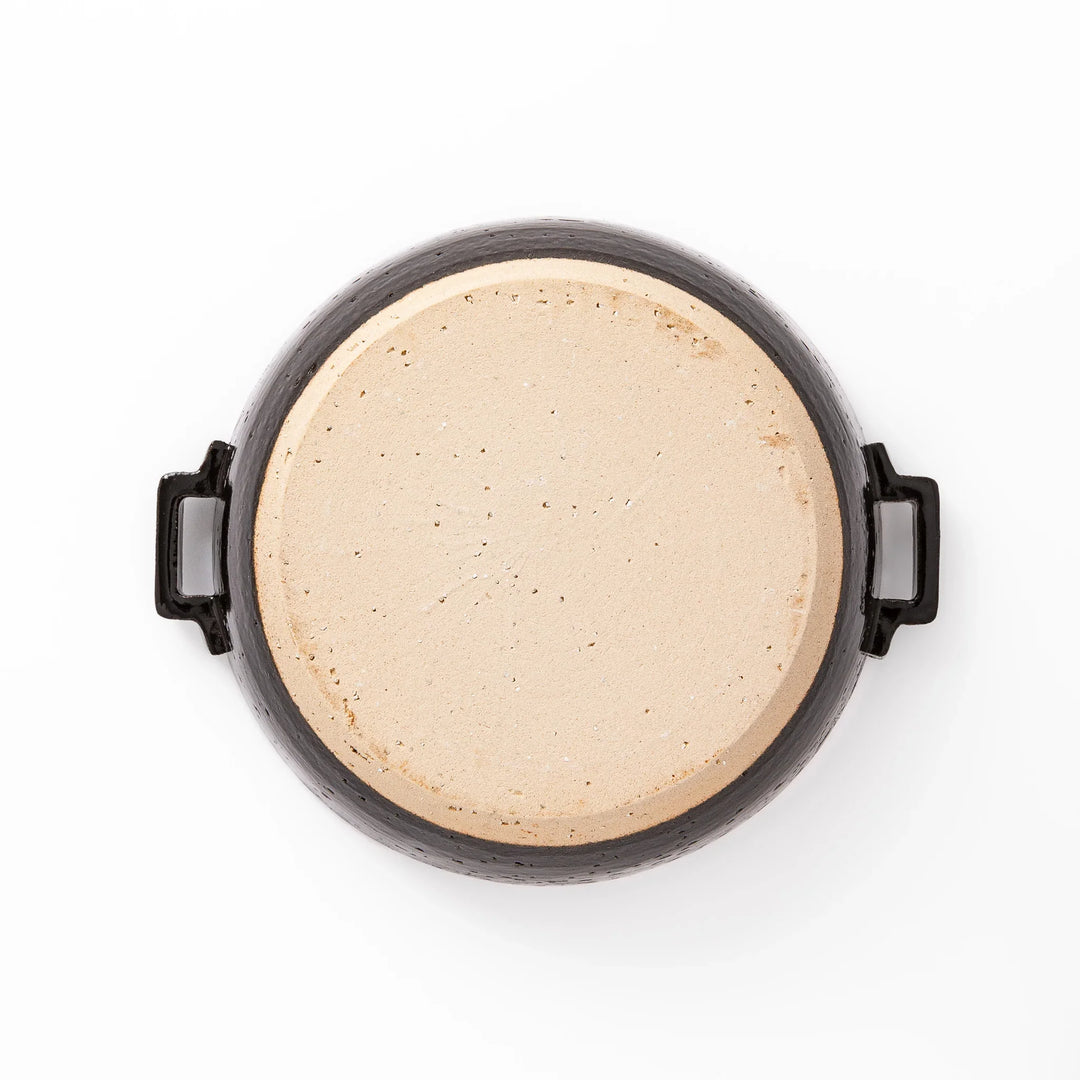 Black Japanese ceramic donabe pot with lid and side handles for simmering and hot pot cooking