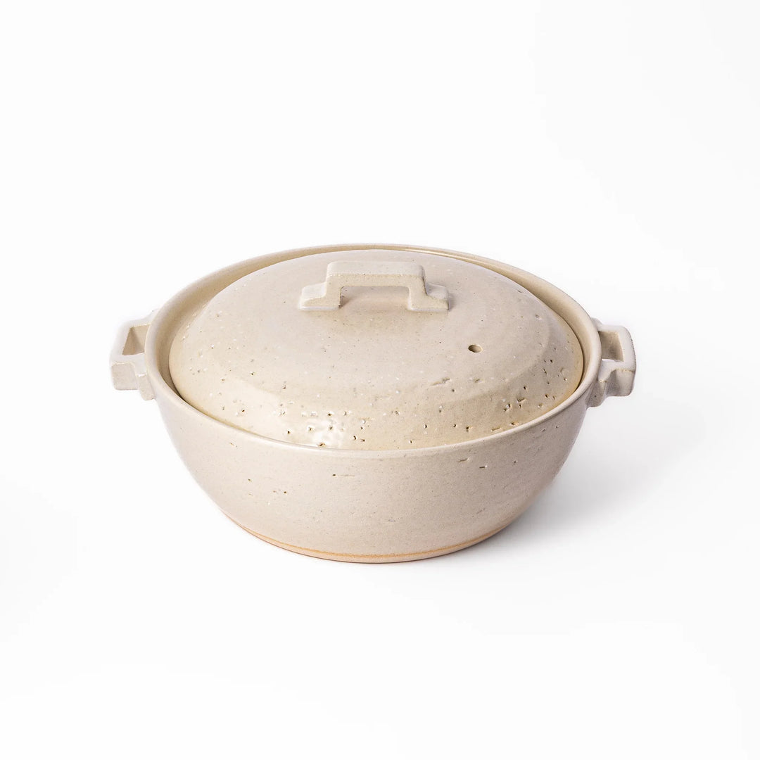 White Japanese donabe with a vented lid and side handles made of rustic handcrafted ceramic