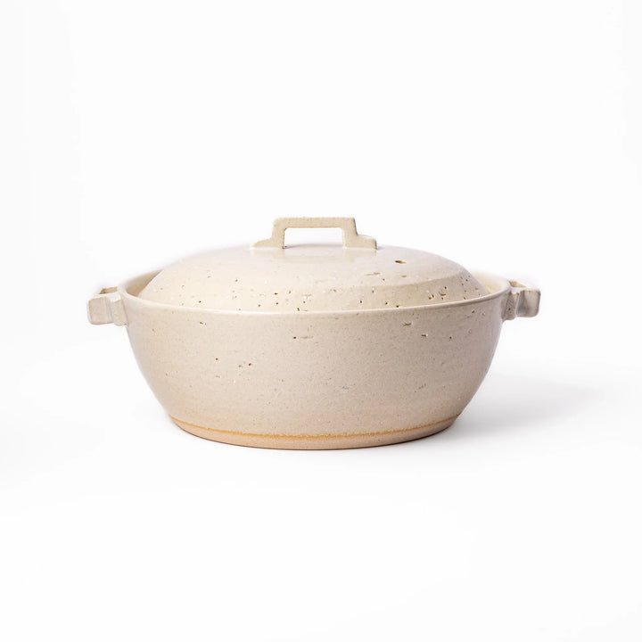 White Japanese donabe with a vented lid and side handles made of rustic handcrafted ceramic