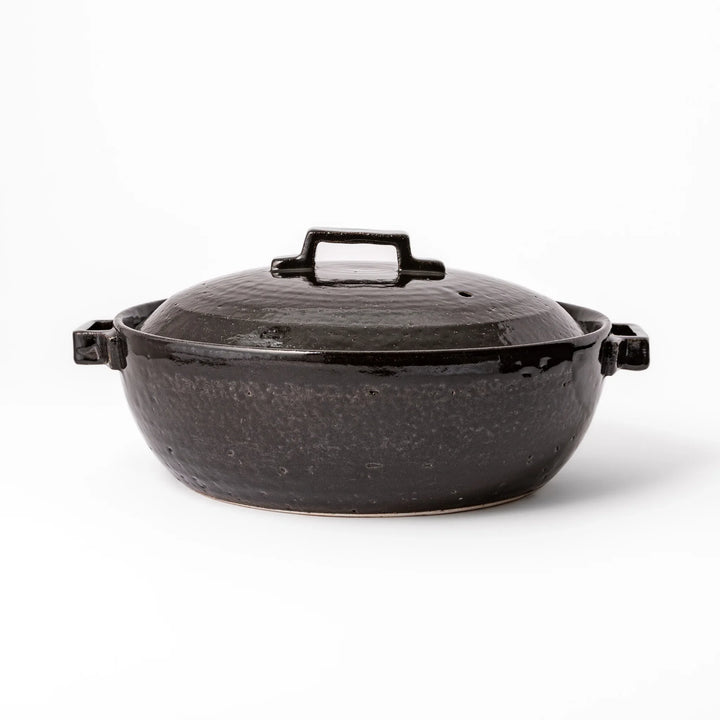 Black Japanese ceramic donabe with a fitted lid and side handles for family size hot pot and stovetop cooking