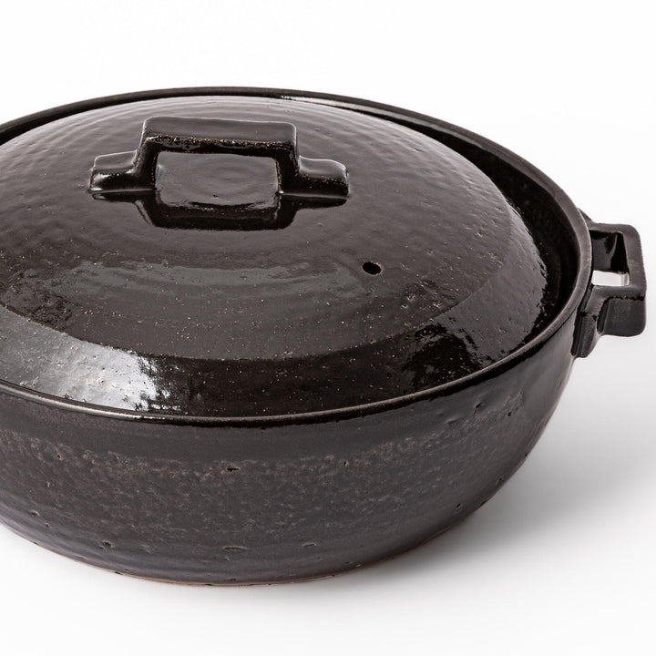Black Japanese ceramic donabe with a fitted lid and side handles for family size hot pot and stovetop cooking