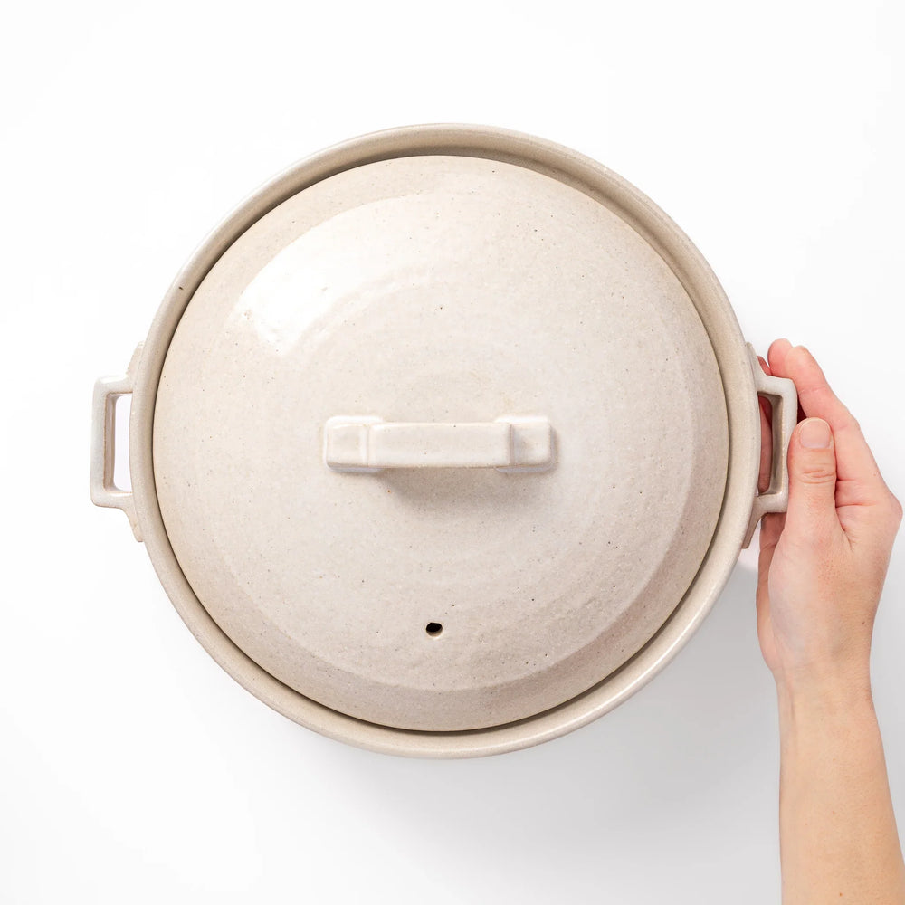 Beige Japanese ceramic family size donabe with a fitted lid and side handles for stovetop cooking and hot pot meals