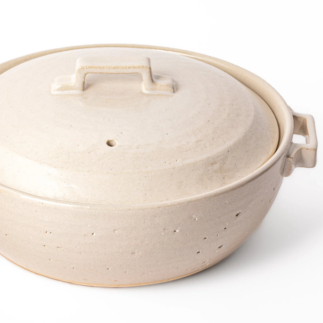 Beige Japanese ceramic family size donabe with a fitted lid and side handles for stovetop cooking and hot pot meals