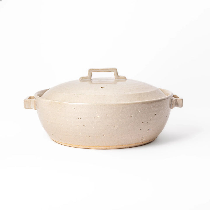 Beige Japanese ceramic family size donabe with a fitted lid and side handles for stovetop cooking and hot pot meals