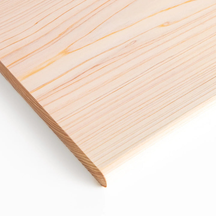 Hinoki wood cutting board with natural grain, engraved logo, and attached base for upright storage, combining beauty with everyday function.
