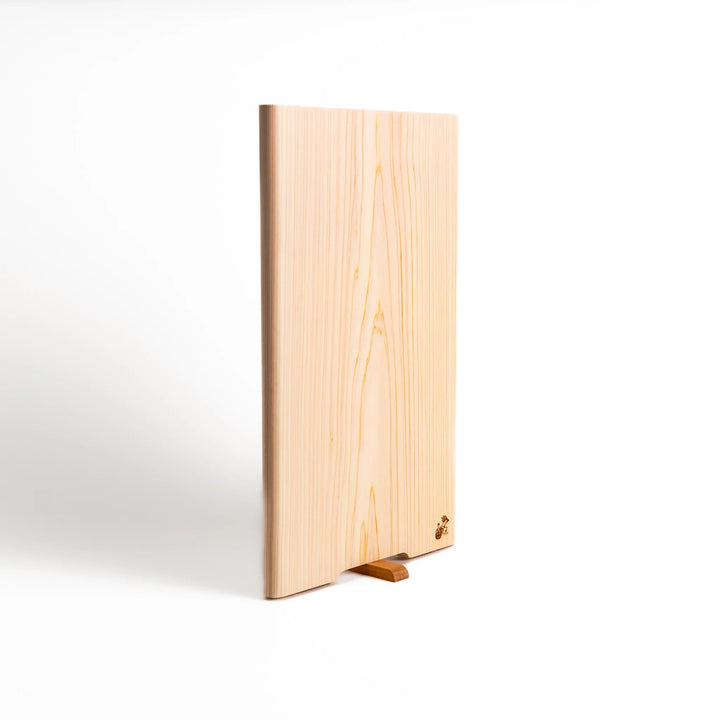 Hinoki wood cutting board with a built-in stand and engraved corner logo, showcasing natural grain and ideal for clean, stylish prep work.