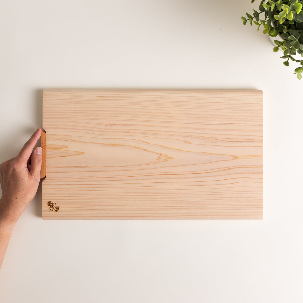 Hinoki wood cutting board with a built-in stand and engraved corner logo, showcasing natural grain and ideal for clean, stylish prep work.