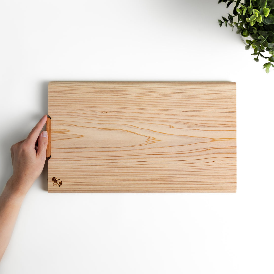 Hinoki wood cutting board with a built-in stand and engraved corner logo, showcasing natural grain and ideal for clean, stylish prep work.