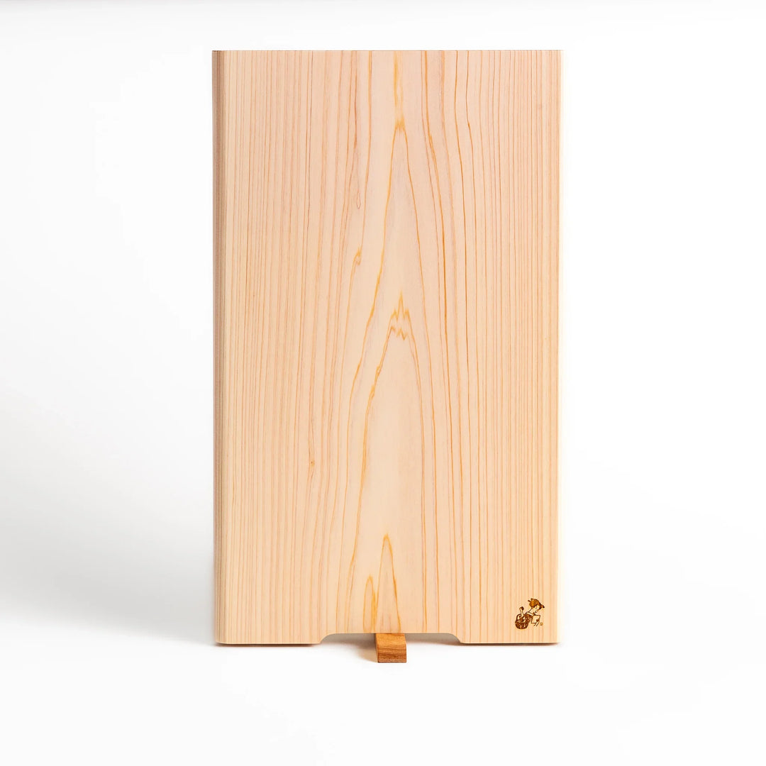 Hinoki wood cutting board with a built-in stand and engraved corner logo, showcasing natural grain and ideal for clean, stylish prep work.