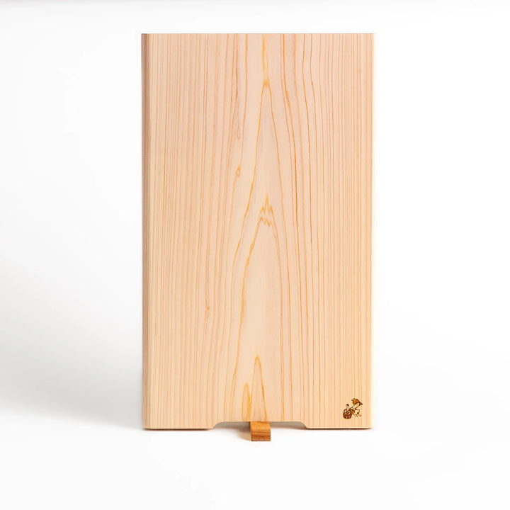 Hinoki wood cutting board with a built-in stand and engraved corner logo, showcasing natural grain and ideal for clean, stylish prep work.
