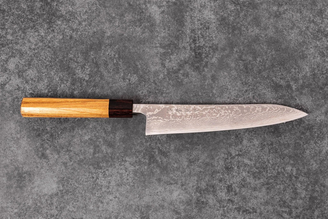 Japanese Damascus chef knife with a wooden handle displayed on a textured gray surface
