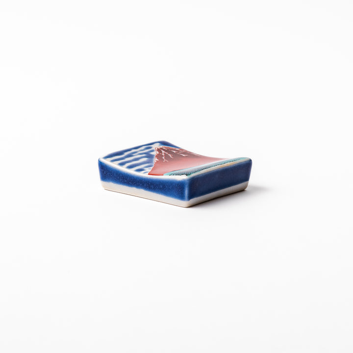 Rectangular Japanese ceramic chopstick rest featuring Hokusai’s Red Fuji design with vivid red mountain and blue sky, bringing iconic artistry to dining tables.
