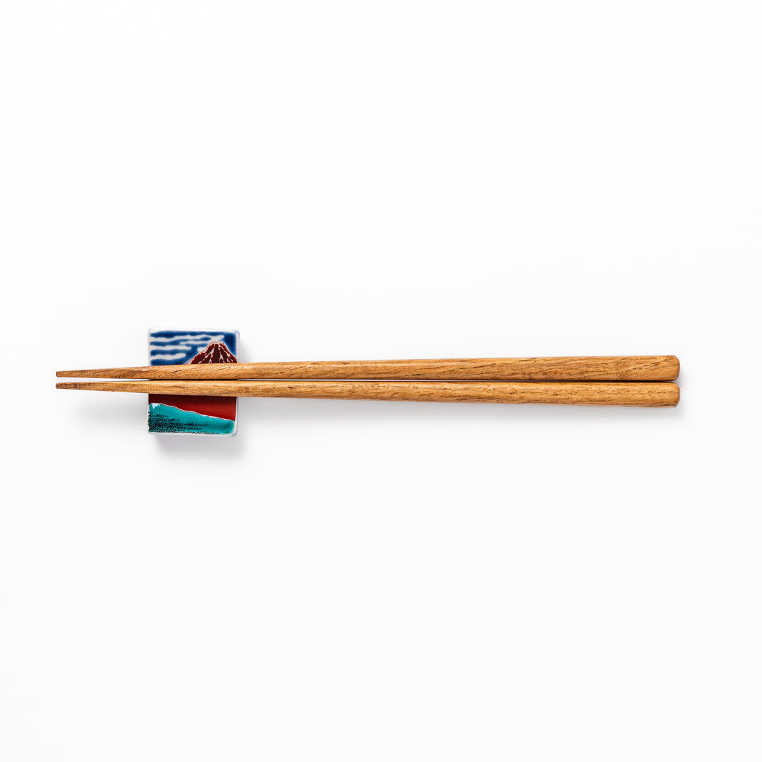 Rectangular Japanese ceramic chopstick rest featuring Hokusai’s Red Fuji design with vivid red mountain and blue sky, bringing iconic artistry to dining tables.
