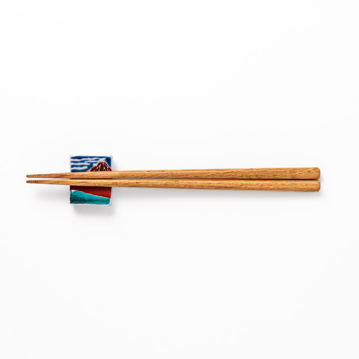 Rectangular Japanese ceramic chopstick rest featuring Hokusai’s Red Fuji design with vivid red mountain and blue sky, bringing iconic artistry to dining tables.