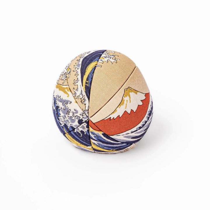 Fabric daruma ornament with bold Kabuki style face and wave pattern set on a small wooden display stand