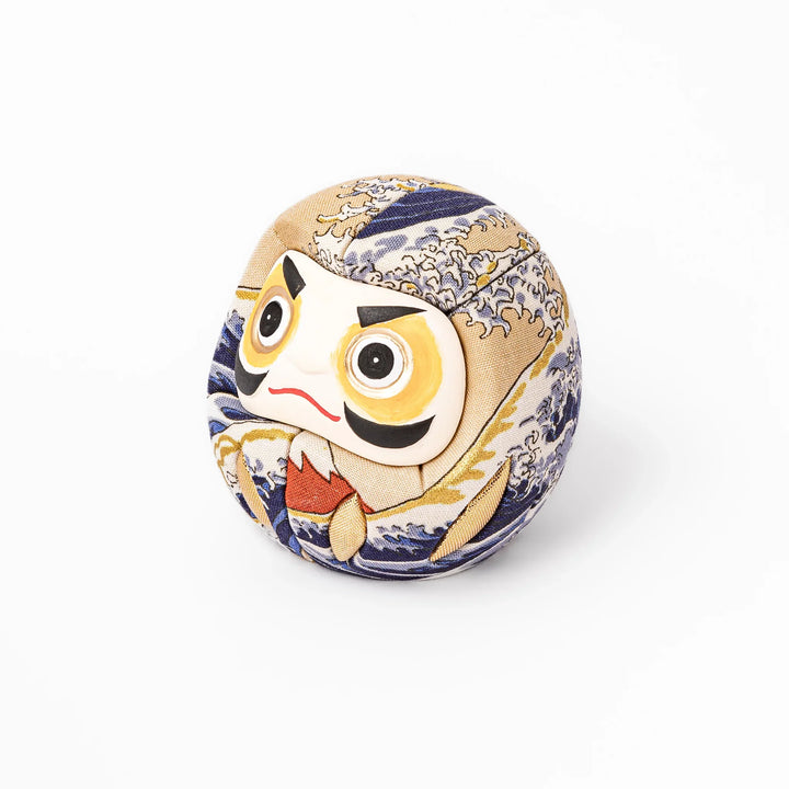 Fabric daruma ornament with bold Kabuki style face and wave pattern set on a small wooden display stand