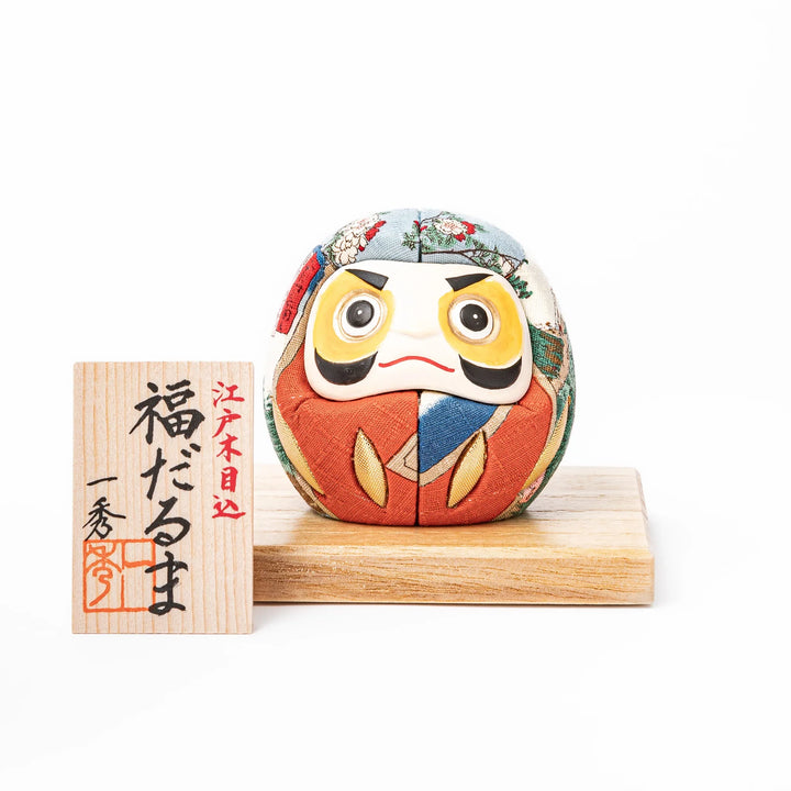 Fabric daruma ornament with bright multicolor kimono pattern and bold painted face displayed on a wooden stand