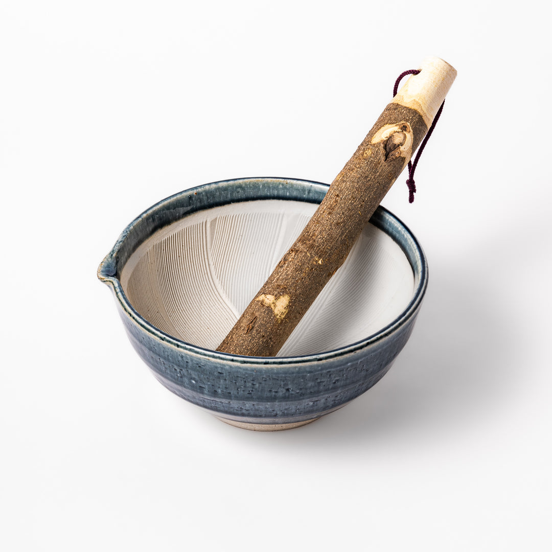 Indigo glaze suribachi mortar with cream grooved interior and rustic wooden pestle, perfect for grinding sesame seeds and Japanese seasonings.