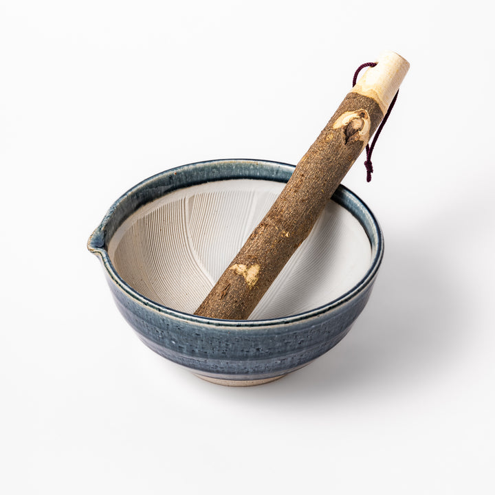 Indigo glaze suribachi mortar with cream grooved interior and rustic wooden pestle, perfect for grinding sesame seeds and Japanese seasonings.