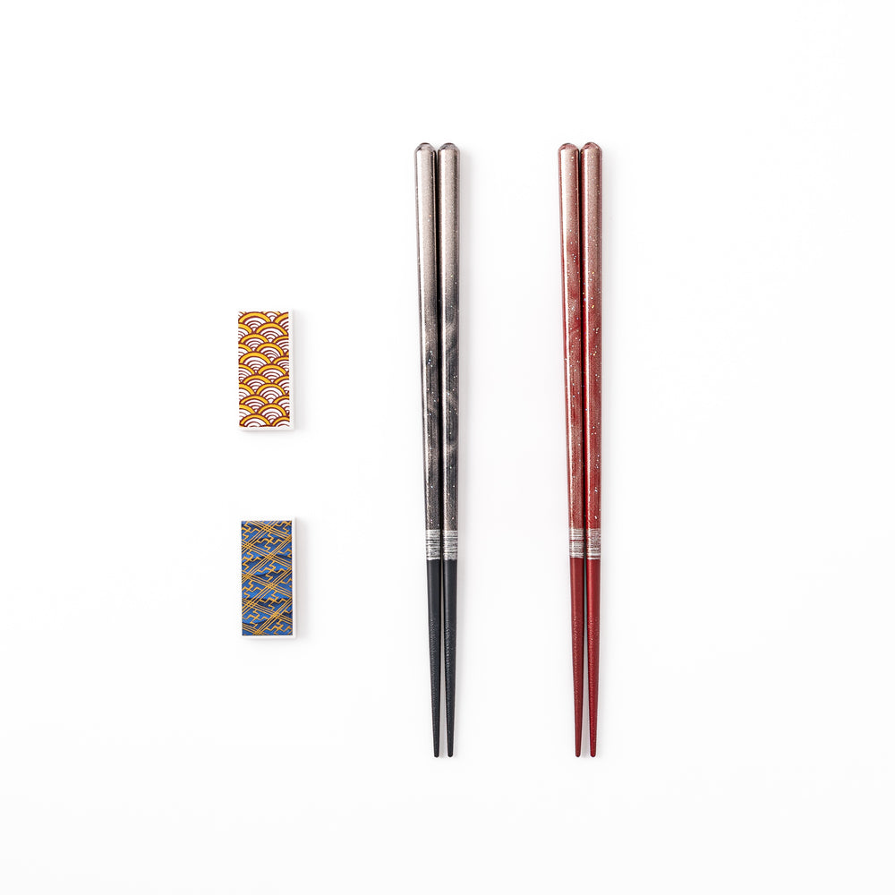 A pair of black and red lacquer Japanese chopsticks with two rectangular ceramic chopstick rests featuring traditional patterns