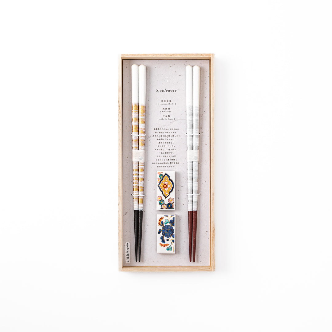 A pair of gold and silver textured Japanese chopsticks with two rectangular ceramic chopstick rests featuring floral patterns