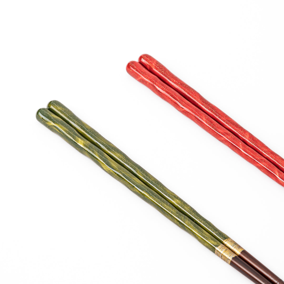 Close up of green and red Japanese chopsticks with subtle gold sparkles and a smooth glossy lacquer finish on the handles