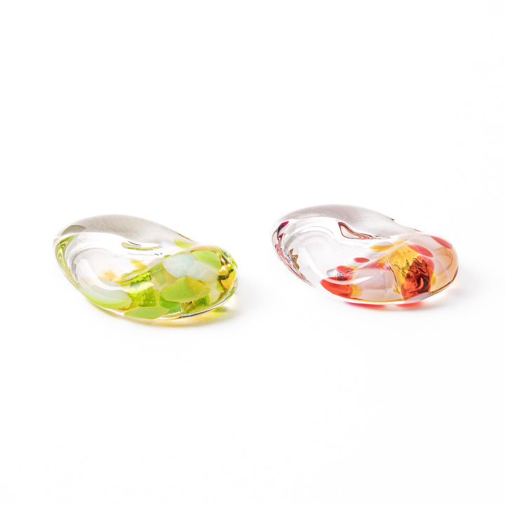 Two pebble shaped Tsugaru Vidro glass chopstick rests featuring translucent clear glass infused with green red and gold flakes