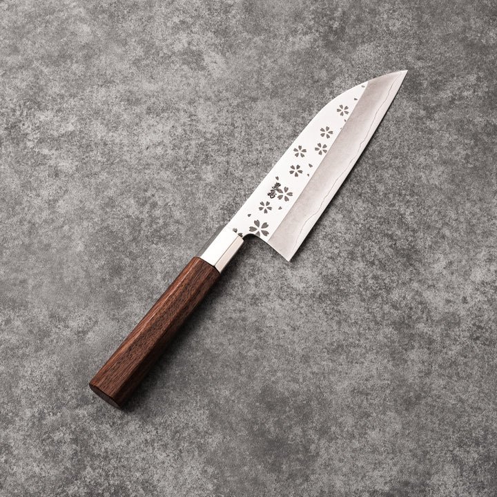 Elegant Japanese kitchen knife with cherry blossom cutout pattern on the blade, featuring a sharp edge and dark wooden handle for precise cutting.
