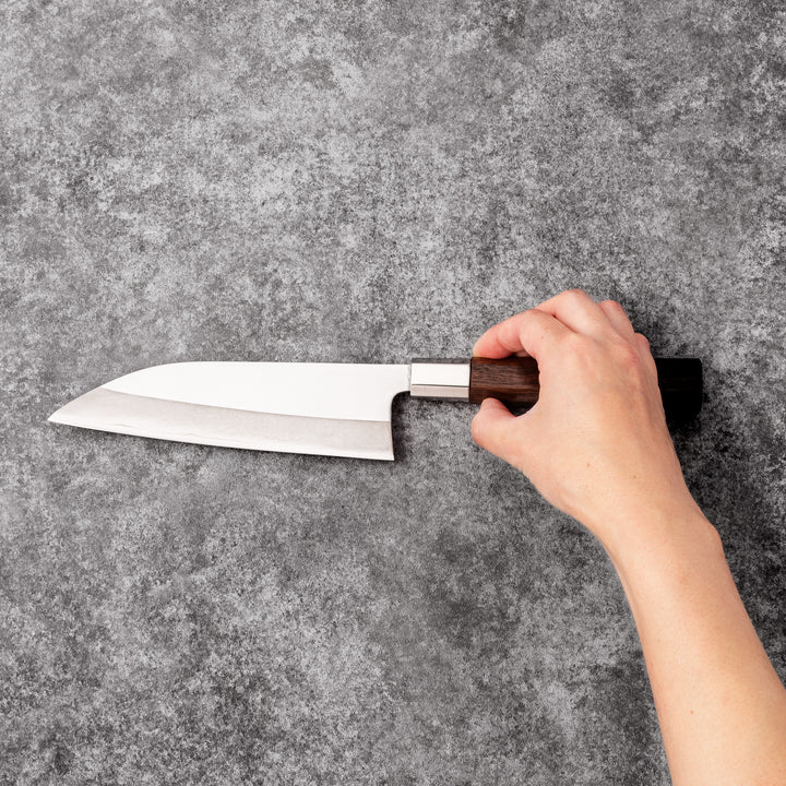 Elegant Japanese kitchen knife with cherry blossom cutout pattern on the blade, featuring a sharp edge and dark wooden handle for precise cutting.