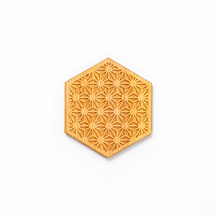 Hexagon hinoki wood coaster with engraved hemp star pattern on a white background.