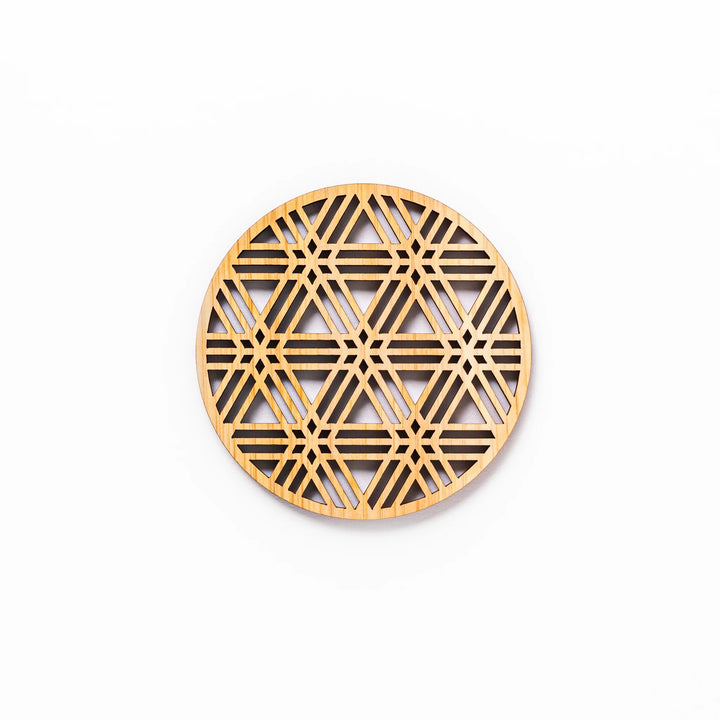 Round hinoki wood coaster with a sesame lattice cutout pattern, showcasing intricate geometric Japanese design.