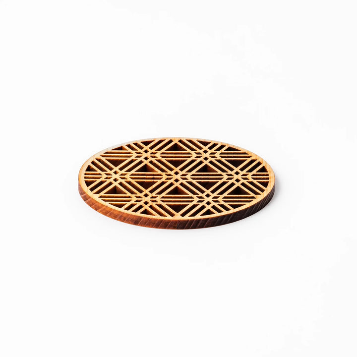 Round hinoki wood coaster with a sesame lattice cutout pattern, showcasing intricate geometric Japanese design.