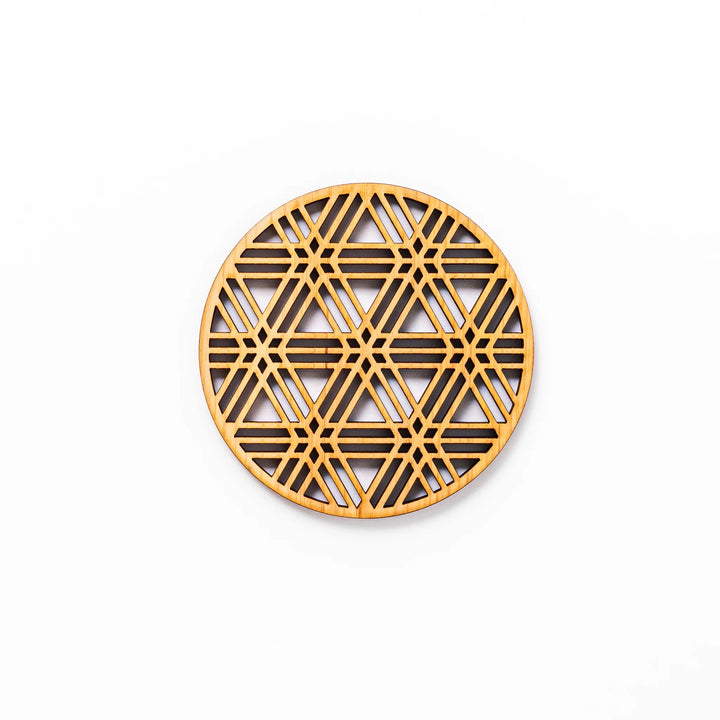 Round hinoki wood coaster with a sesame lattice cutout pattern, showcasing intricate geometric Japanese design.