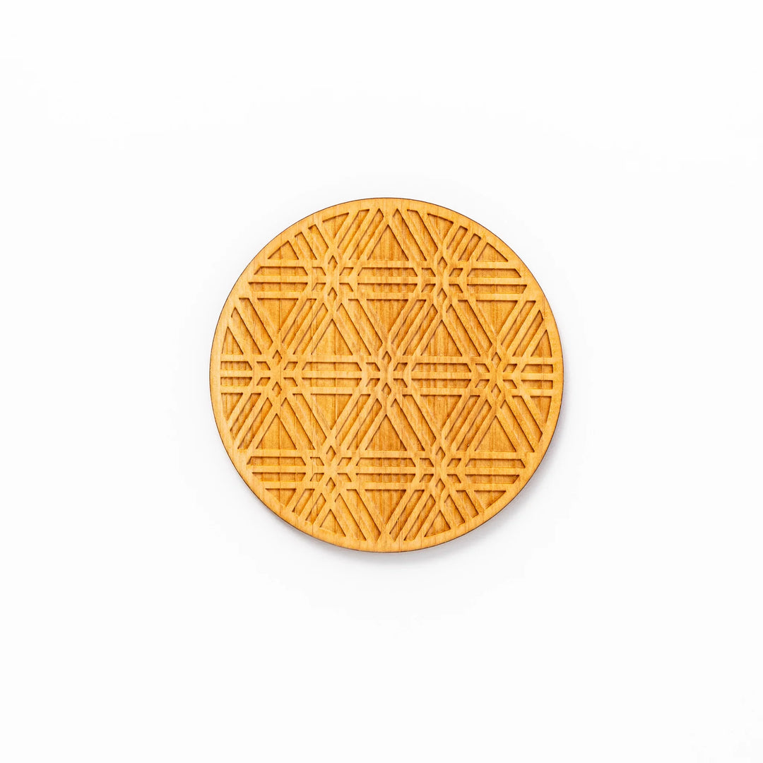 Round hinoki wood coaster with engraved sesame lattice pattern, featuring warm natural grain and a finely detailed geometric design.