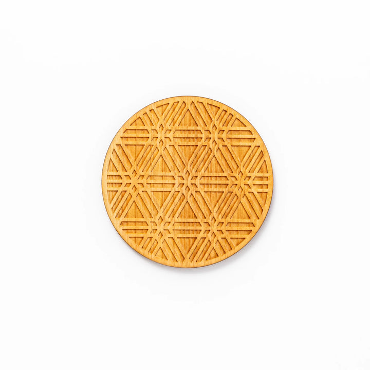 Round hinoki wood coaster with engraved sesame lattice pattern, featuring warm natural grain and a finely detailed geometric design.