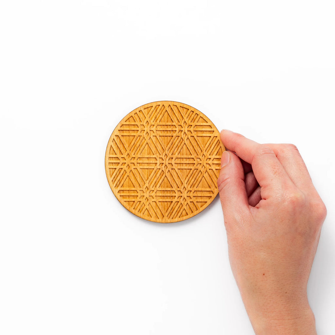 Round hinoki wood coaster with engraved sesame lattice pattern, featuring warm natural grain and a finely detailed geometric design.