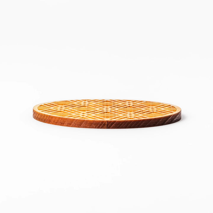 Round hinoki wood coaster with engraved sesame lattice pattern, featuring warm natural grain and a finely detailed geometric design.