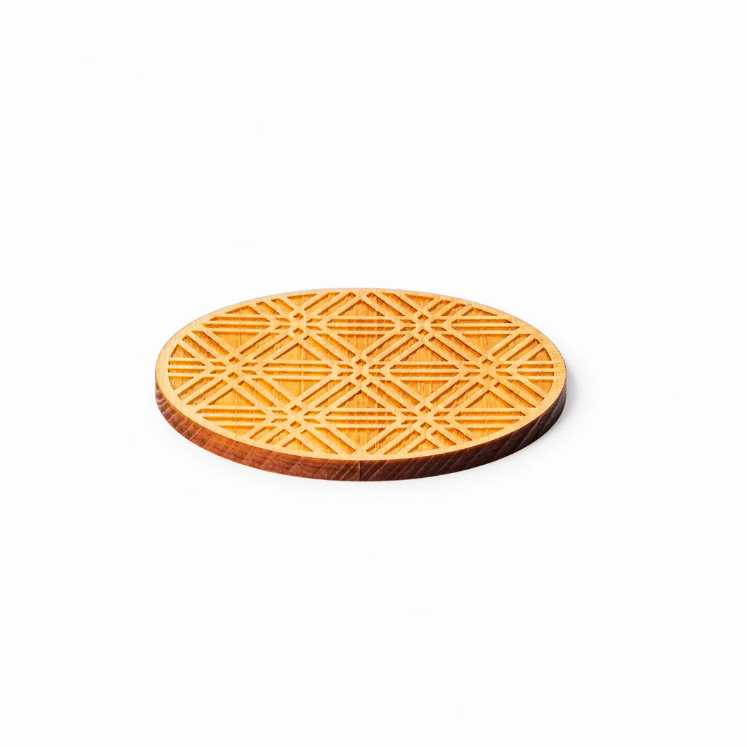 Round hinoki wood coaster with engraved sesame lattice pattern, featuring warm natural grain and a finely detailed geometric design.