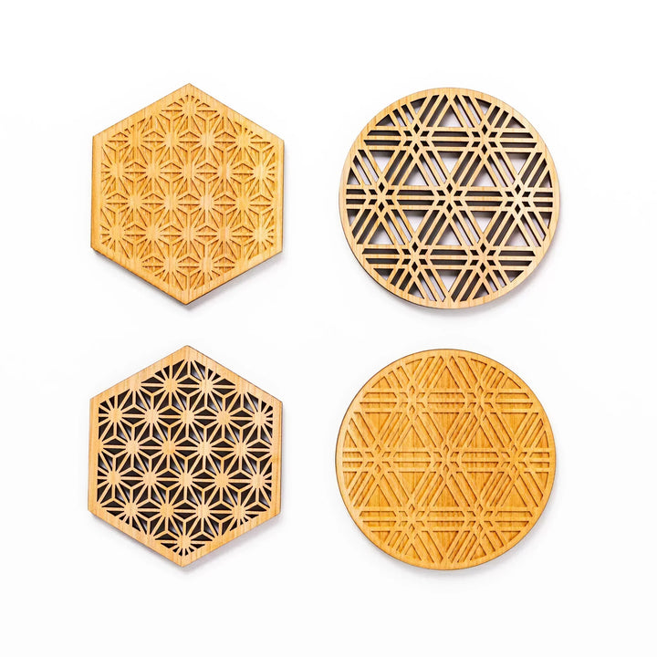 Four hinoki wood coasters with intricate hexagonal and circular lattice patterns displayed on a white background.