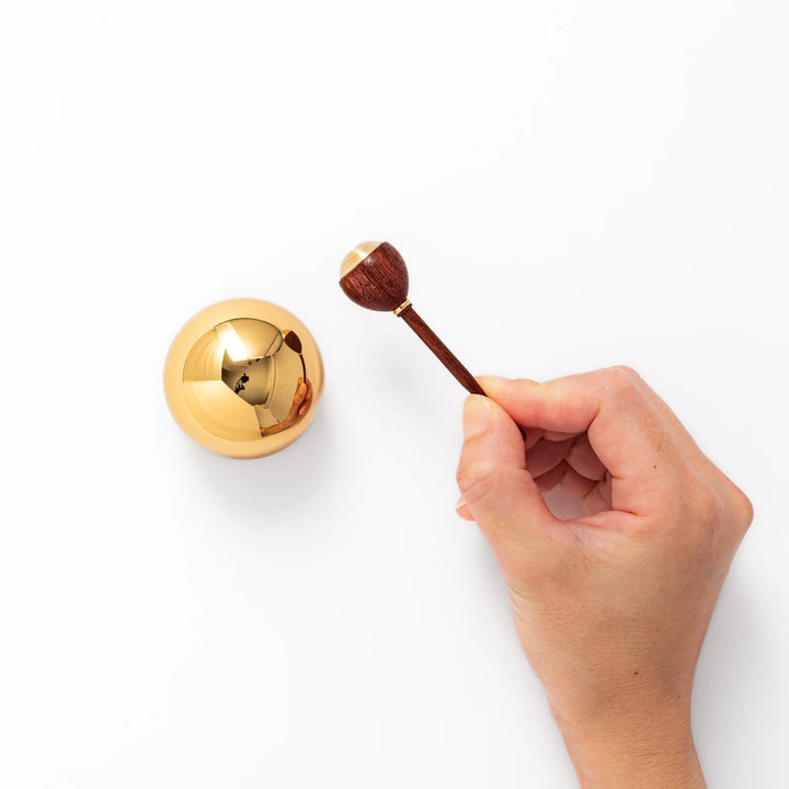 Japanese meditation and prayer chime with golden dome bell and wooden striker for mindfulness rituals.