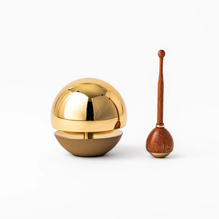 Japanese meditation and prayer chime with golden dome bell and wooden striker for mindfulness rituals.