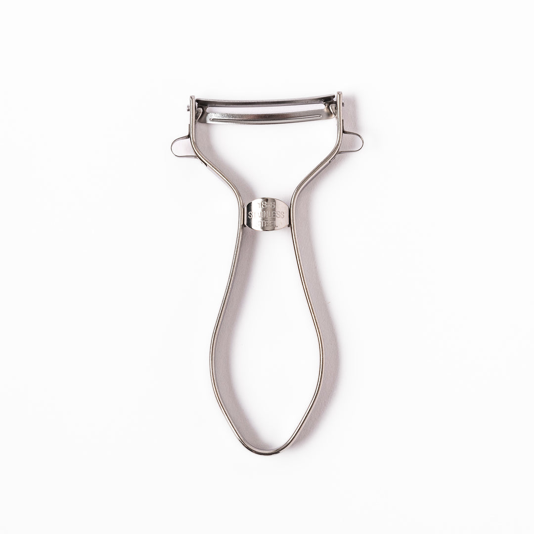 Japanese stainless steel ergonomic peeler with a sharp swivel blade and contoured handle designed for effortless peeling of vegetables and fruits in daily cooking.