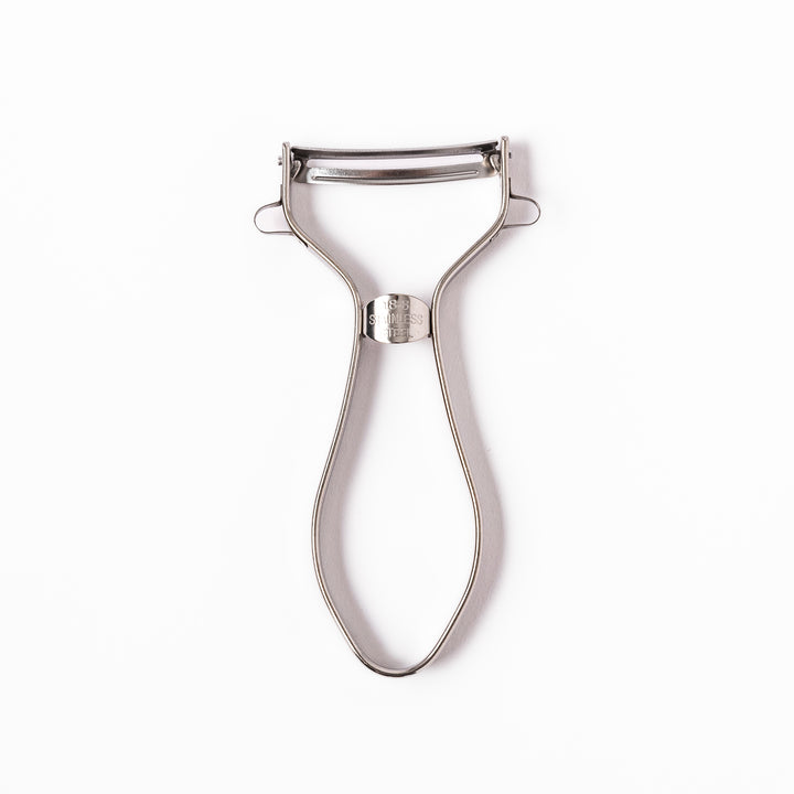 Japanese stainless steel ergonomic peeler with a sharp swivel blade and contoured handle designed for effortless peeling of vegetables and fruits in daily cooking.