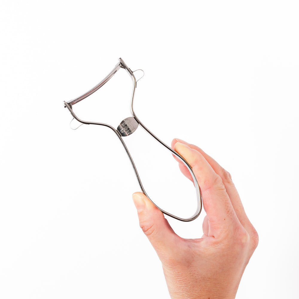 Japanese stainless steel ergonomic peeler with a sharp swivel blade and contoured handle designed for effortless peeling of vegetables and fruits in daily cooking.