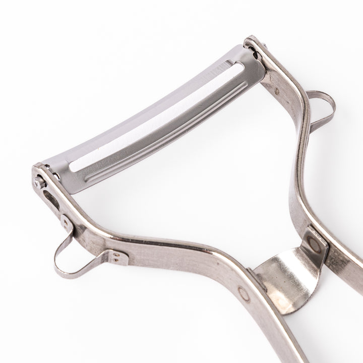 Japanese stainless steel ergonomic peeler with a sharp swivel blade and contoured handle designed for effortless peeling of vegetables and fruits in daily cooking.