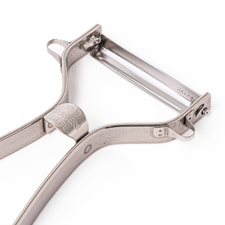 Japanese stainless steel ergonomic peeler with a sharp swivel blade and contoured handle designed for effortless peeling of vegetables and fruits in daily cooking.